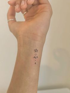 a woman's arm with a small tattoo on it that has flowers in the middle