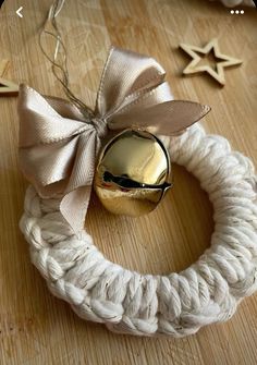 a white rope wreath with a bell on top and star decorations in the back ground