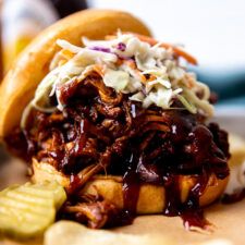 a pulled pork sandwich with cole slaw and pickles