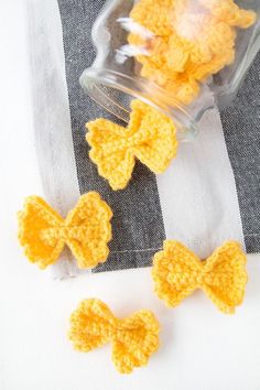 three crocheted bows sitting on top of a striped cloth next to a jar