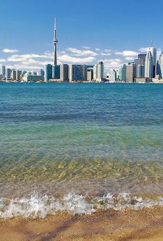 the city skyline as seen from across the water on a sunny day with waves coming in