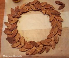 a close up of a wreath made out of wood chips on a table with a bottle of wine in the background