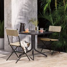 two chairs and a table in front of some plants