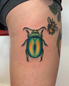 a colorful beetle tattoo on the thigh