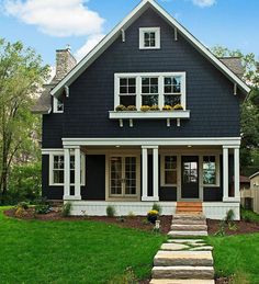 a black and white house with steps leading up to the front door, grass in front yard