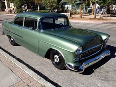 an old green car is parked on the street