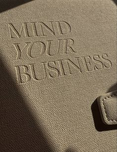 the word mind your business written in sand