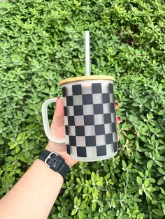 a hand holding a coffee cup with a black and white checkerboard pattern on it