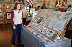 a woman standing next to a table with pictures on it and other items for sale