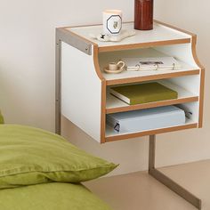 a small table with some books and a cup on it next to a green pillow