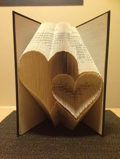 an open book with two hearts cut out of it and pages folded in the shape of books