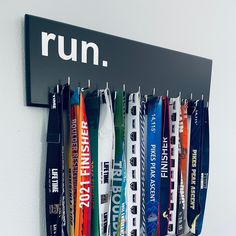 a row of medals hanging from a wall next to a sign that says run on it