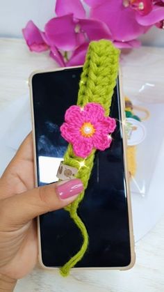 a person holding a cell phone with a crocheted flower on it