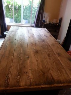 a large wooden table sitting in front of a window