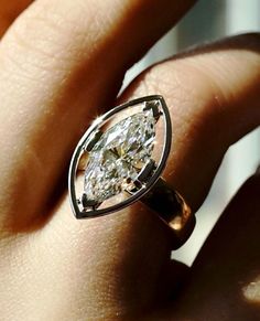 a woman's hand holding a ring with a pear shaped diamond in the center