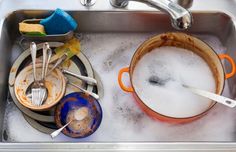 dirty dishes and utensils in a stainless steel sink