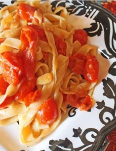 pasta with tomatoes and sauce on a black and white plate