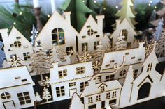 a group of wooden houses sitting on top of a table next to christmas trees and candles