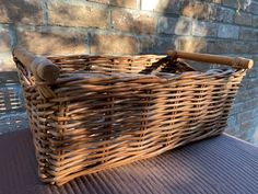 a wicker basket sitting on top of a table next to a brick wall with a wooden handle