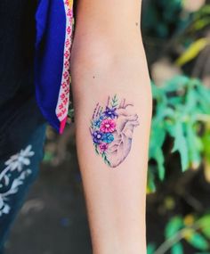 a woman's arm with a tattoo on it that has flowers in the heart