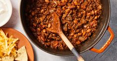 a pot filled with chili and beans next to tortilla chips on a table