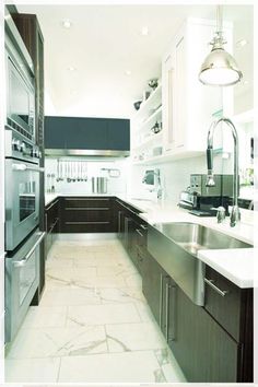 a large kitchen with stainless steel appliances and marble counter tops, along with dark wood cabinets