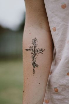 a person with a cross tattoo on their left arm and the other arm is in front of her