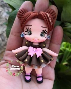 a hand holding a small doll with brown hair and pink dress on it's face