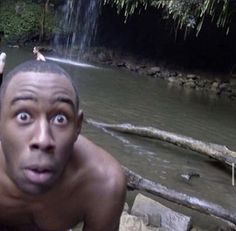 two men are in the water near a waterfall