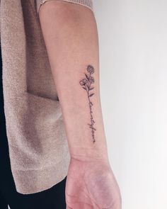 a woman's arm with a small flower tattoo on the left side of her wrist