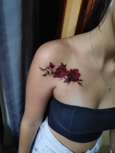 a woman's chest with red roses tattooed on her left arm and the bottom part of her right shoulder