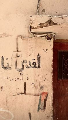 graffiti on the side of a building in an arabic language, with a door and window