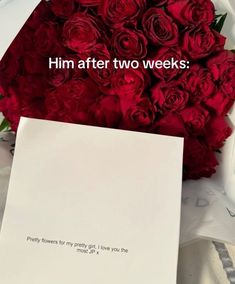 a bouquet of red roses sitting on top of a table next to a piece of paper