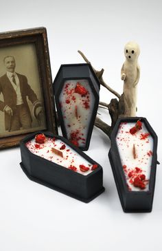 three miniature items are displayed in front of an old photo and frame with blood on them