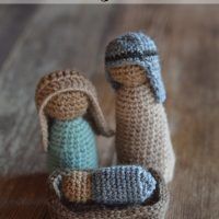 two crocheted nativity dolls sitting next to each other on a wooden table