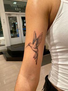 a woman's arm with a small tattoo of a hummingbird on the left arm