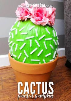 a green cactus with white sprinkles and pink flowers in a clay pot