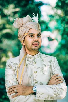 a man wearing a turban and standing with his arms crossed in front of him