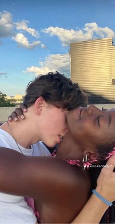 two young women are taking a selfie in front of a building with blue skies and white clouds