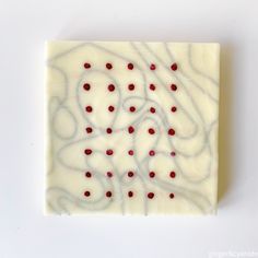 a square piece of white and red art with dots on it's surface that looks like something out of space