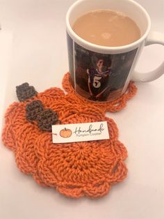 an orange knitted coaster next to a cup of coffee