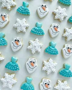 frosted cookies decorated like snowmen and hats on a white surface with blue icing