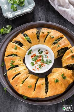 a plate that has some bread on it and a bowl in the middle with sauce