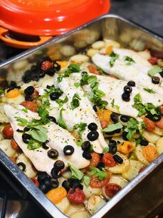 fish with olives, tomatoes and other vegetables in a pan on top of the stove