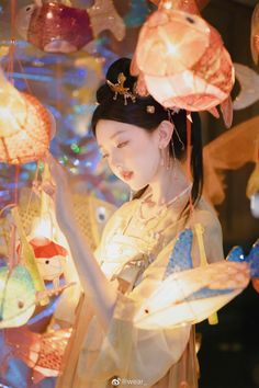 a woman is looking at some lights in the shape of fish and other things hanging from her head