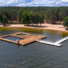 an aerial view of a dock in the middle of a body of water with trees around it