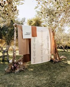 an outdoor ceremony setup with brown and white linens, flowers and greenery on the grass