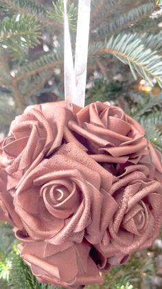 an ornament hanging from a christmas tree decorated with pink roses and ribbones