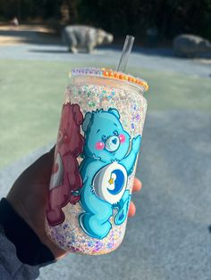 a person holding up a cup with a bear on it and a straw in the other hand