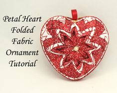 a red heart shaped ornament sitting on top of a white table next to the words metal heart folded in fabric